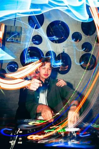 DJ in consolle tra scie di luce colorate